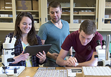 Instructor helping two students in research lab